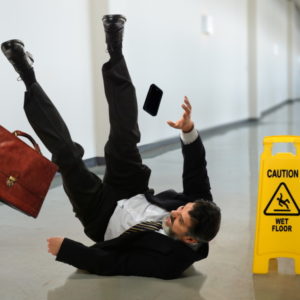 Senior businessman falling near caution sign in hallway