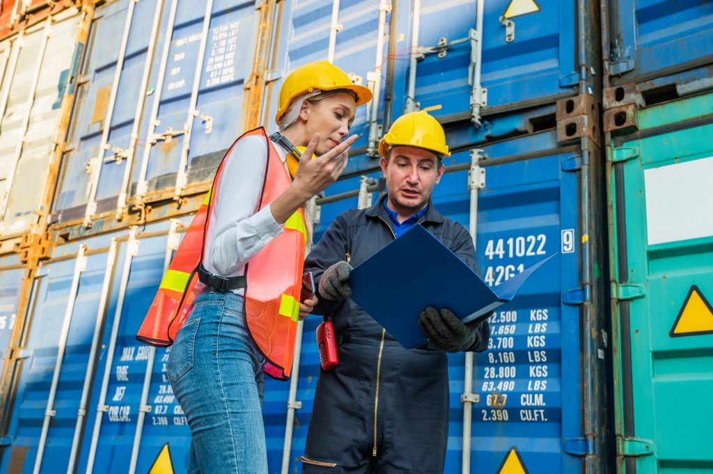 Two foreman man & woman worker talking in front of loading containers.
